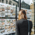 Vue de dos d'une femme observant des annonces immobilières dans la rue » IA générative