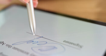 Close-up of female hand signing e-document on tablet with stylus. Electronic signature and modern technologies concept