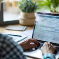 An image of an individual reviewing their tax return online. The person is sitting comfortably at a desk with a laptop, looking over the summary page.