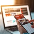 Online news on a smartphone. Mockup website. Woman reading news or articles in a mobile phone screen application at home. Newspaper and portal on internet.