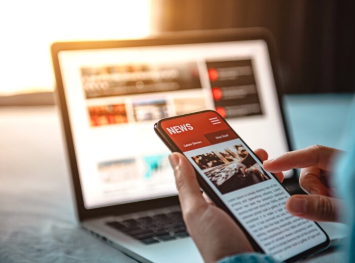 Online news on a smartphone. Mockup website. Woman reading news or articles in a mobile phone screen application at home. Newspaper and portal on internet.