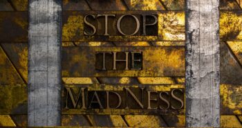 Stop The Madness text formed with real authentic typeset letters on vintage textured silver grunge copper and gold background