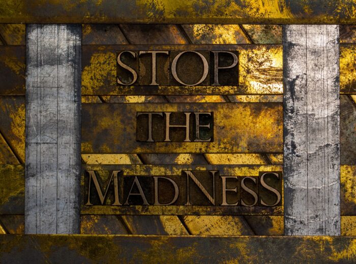 Stop The Madness text formed with real authentic typeset letters on vintage textured silver grunge copper and gold background