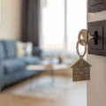 Open door to a new home with key and home shaped keychain. Mortgage, investment, real estate, property and new home concept